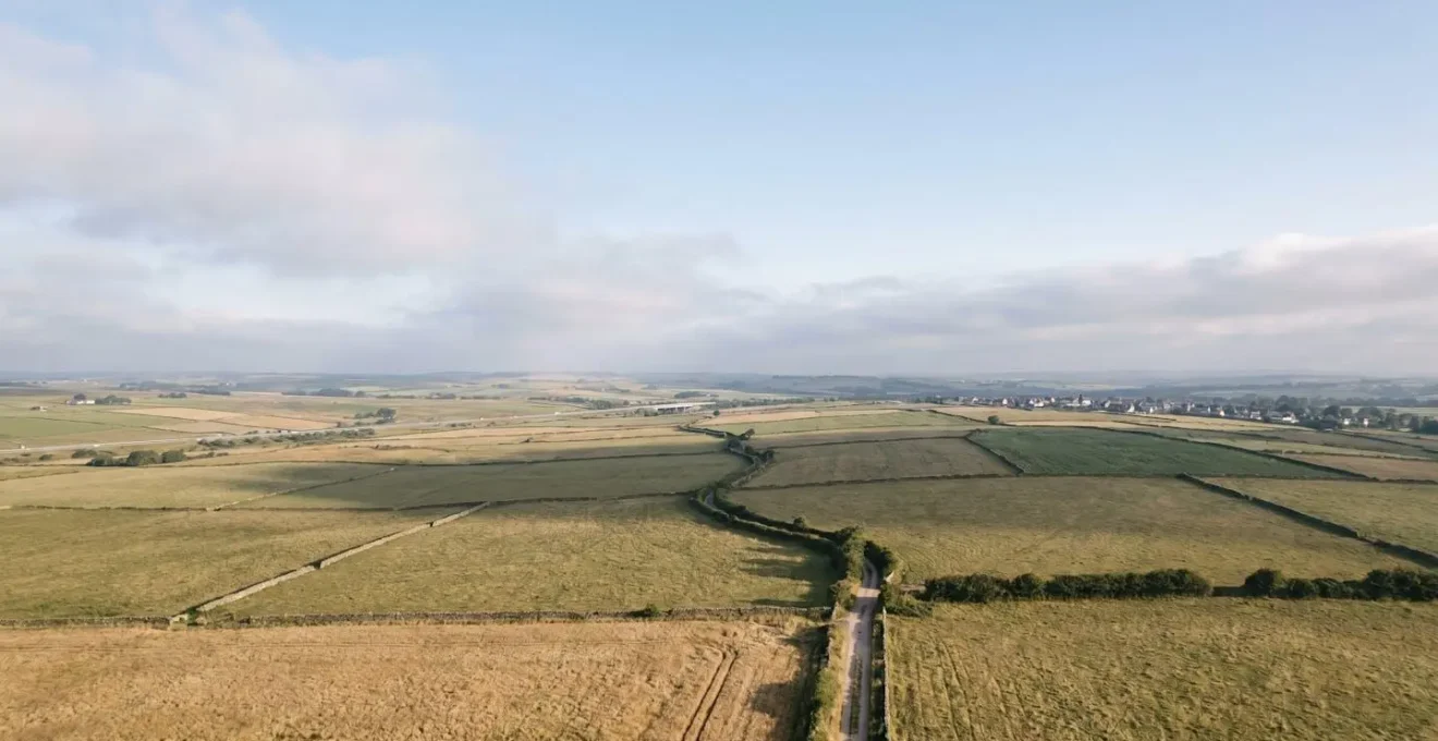 Aerial view of undeveloped land with strategic development potential showing natural landscape transitioning toward urban infrastructure