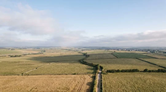 Aerial view of undeveloped land with strategic development potential showing natural landscape transitioning toward urban infrastructure